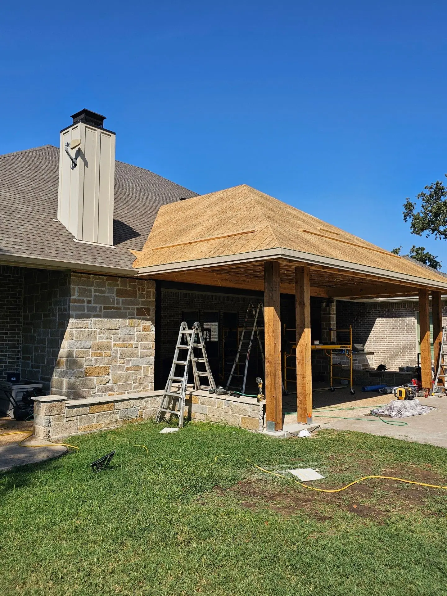 Custom covered patio addition under construction with new framing and roof decking
