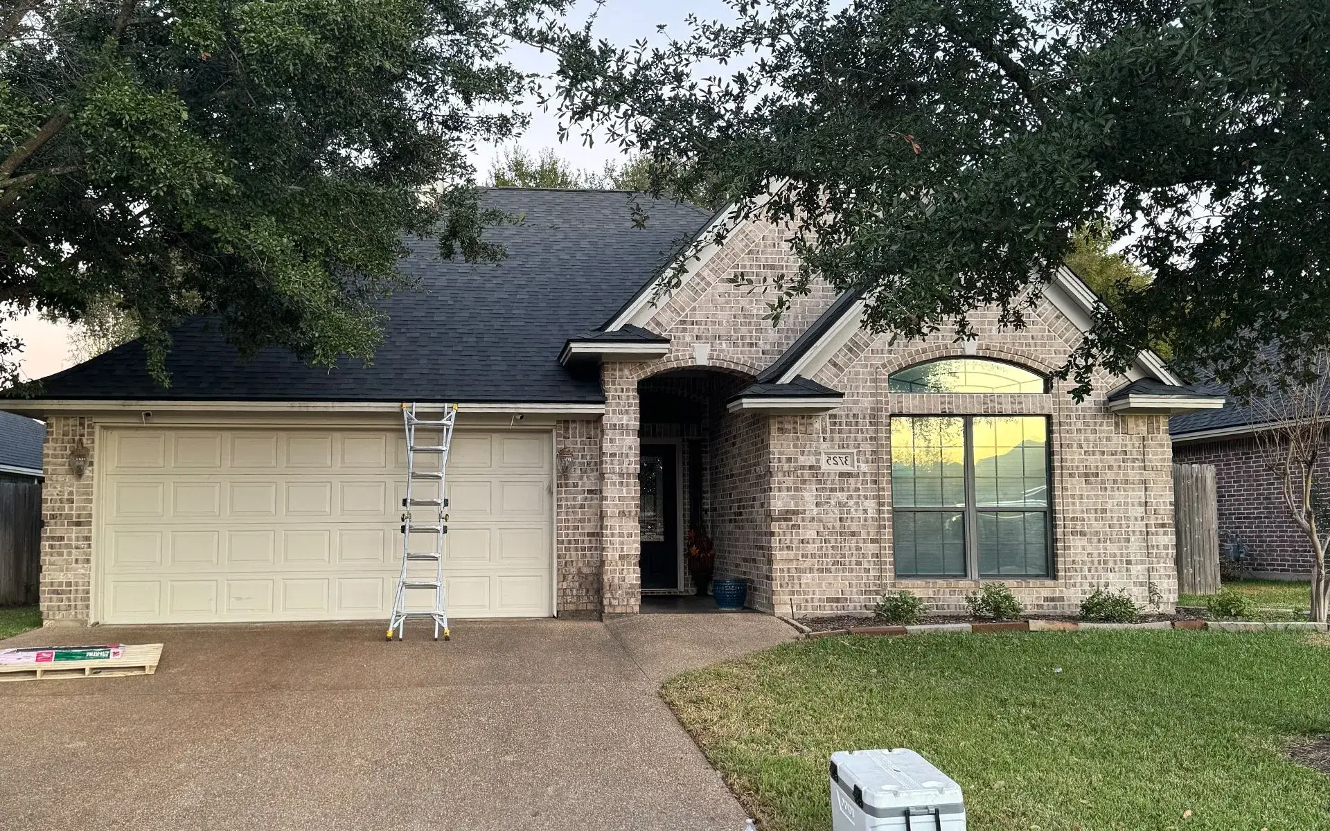 Brick home with a new dark architectural shingle roof installed by Loyalty Roofing